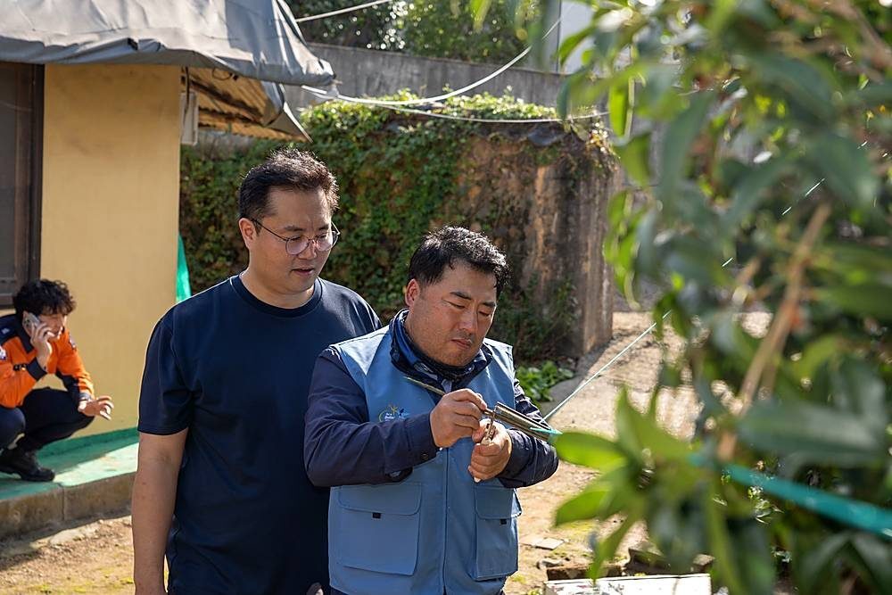주택 마당에서 시공자의 작업을 함께 확인하는 모습, 뒤편에 소방 직원