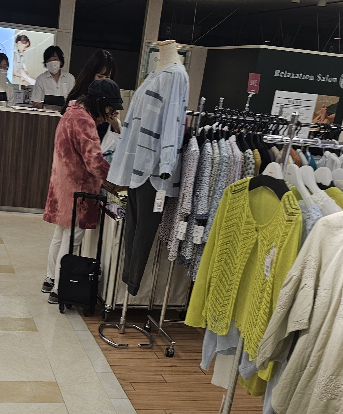 도쿄 게이오백화점 신주쿠점 시니어 매장. 손님이 바퀴 달린 가방을 세워 둔 채 옷을 고르고 있다.